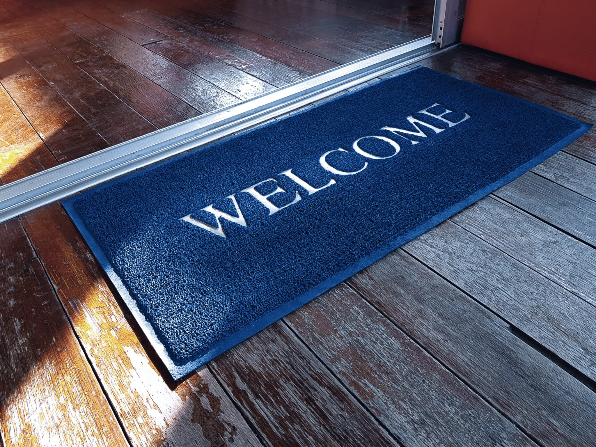 Blue Doormat with Welcome Text in Front of Shop
