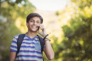 schoolboy using mobile phone in campus at school T4U3KM9